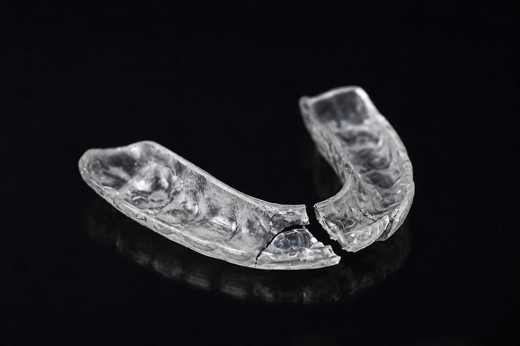 Broken mouthguard on black background