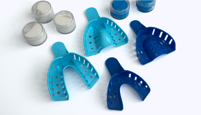Small and large dental impression trays on a white background