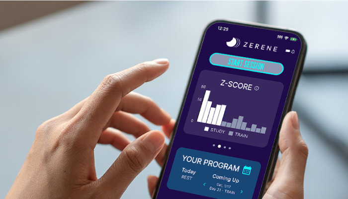 Hand holding a smartphone displaying the Zerene app with a Z-Score graph on the screen.